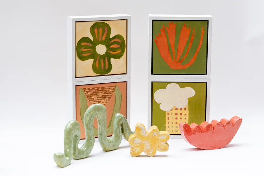 Four small paintings of flower and leaf shapes with three ceramic pieces in front