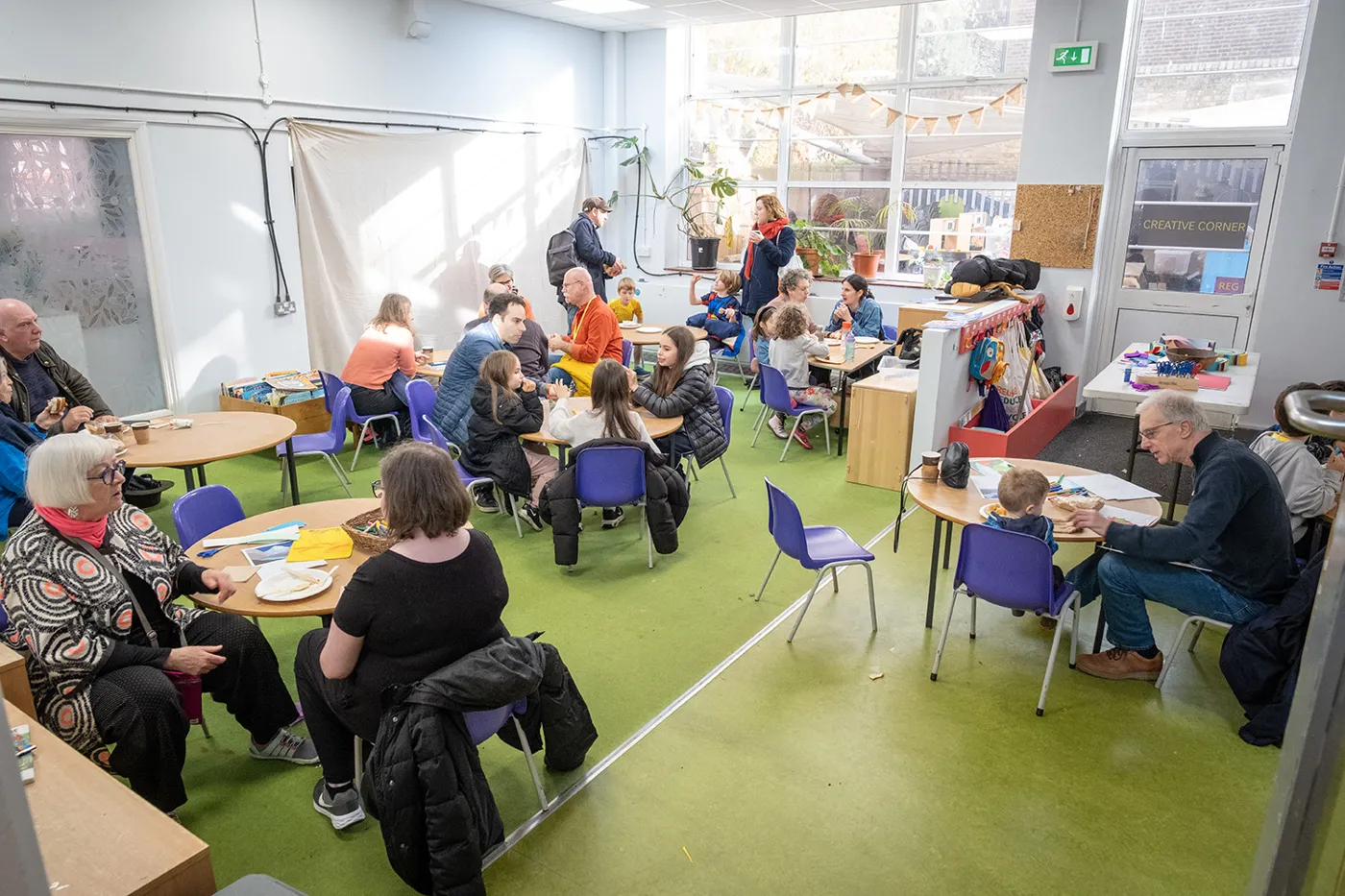 Visitors of all ages sitting at round tables in a bright room